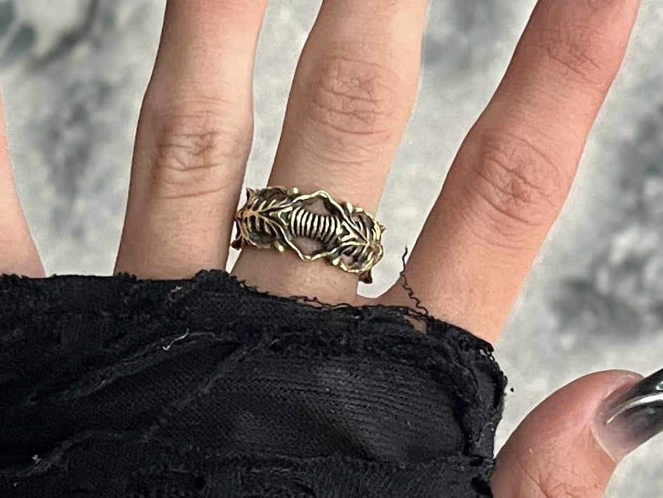 BIOORGA brass ring worn on a hand; Midjourney-retouched stone background with original ring details preserved.